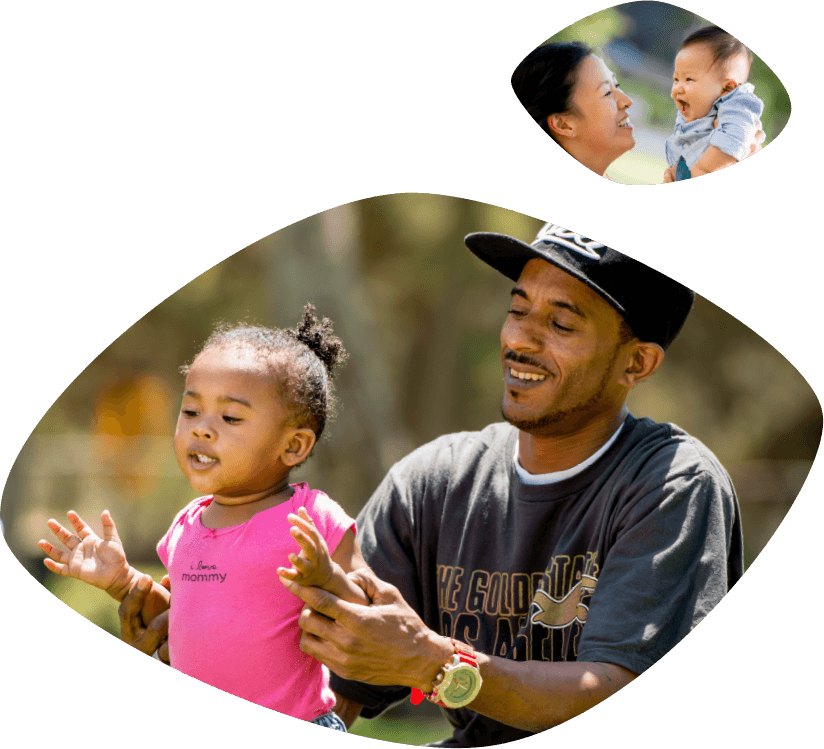 Smiling African Amercan father dressed in tee shirt and baseball hat is helping his smiling daughter stand