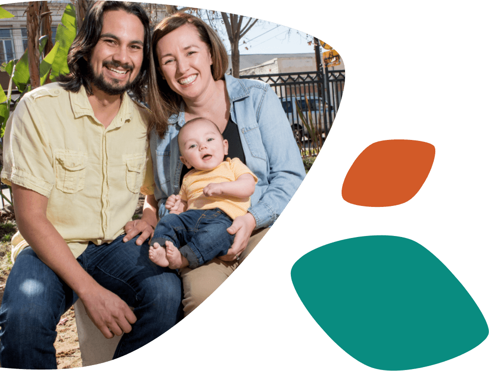 Smiling Hispanic parents sitting with their young son, who is smiling and sitting on the woman's lap