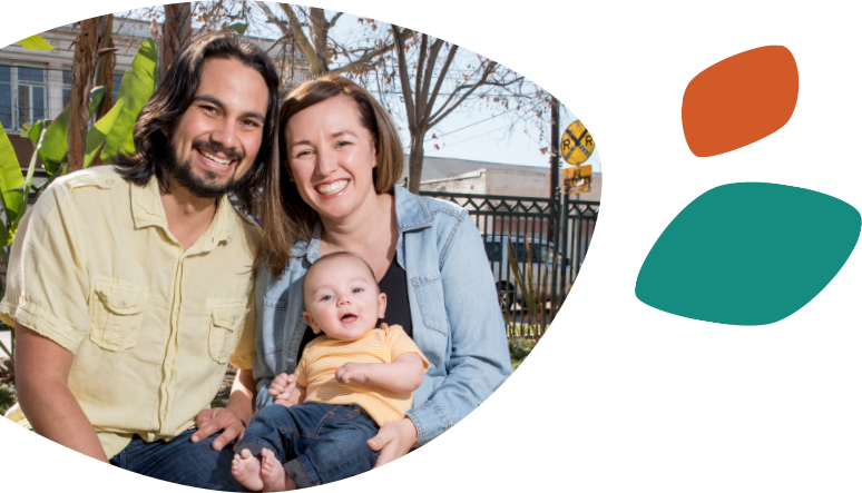 Smiling Hispanic parents sitting with their young son, who is smiling and sitting on the woman's lap