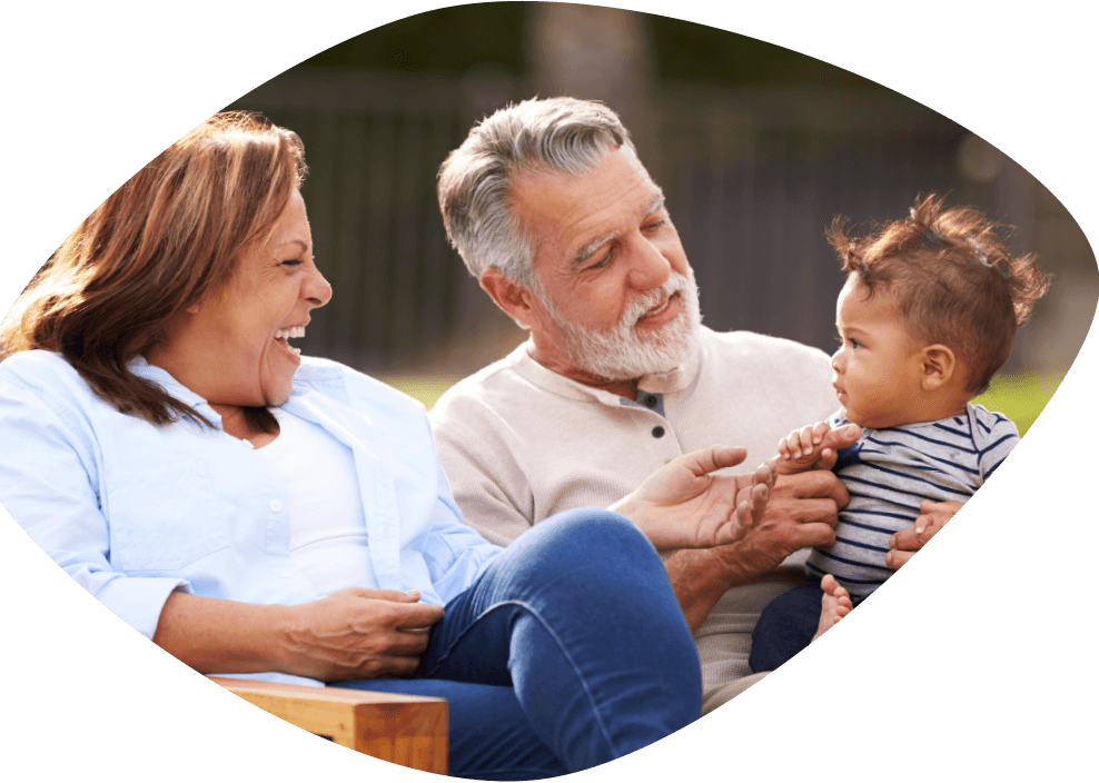 A joyful older woman and man are playing with a toddler who is sitting on the man's lap